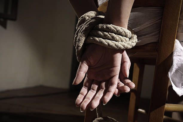 Young woman tied to a chair in a empty room, hands close up